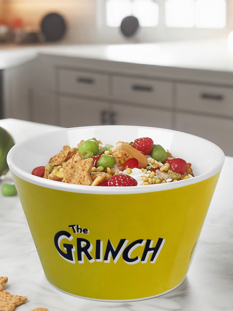 Eine gelbe Grinch-Schüssel gefüllt mit Müsli, Beeren, Nüssen und Joghurt.