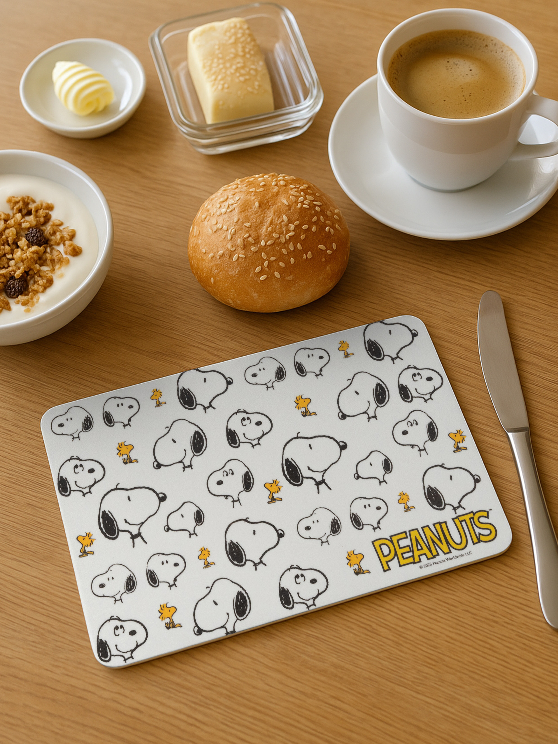 Frühstück mit Kaffee, Joghurt, Brötchen, Butter und Snoopy-Motiv.