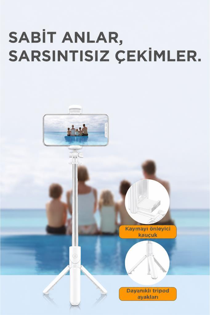 Beyaz selfie çubuğu katlanabilir tripodlu, havuz kenarında bir aileyi gösteren telefon tutuyor.