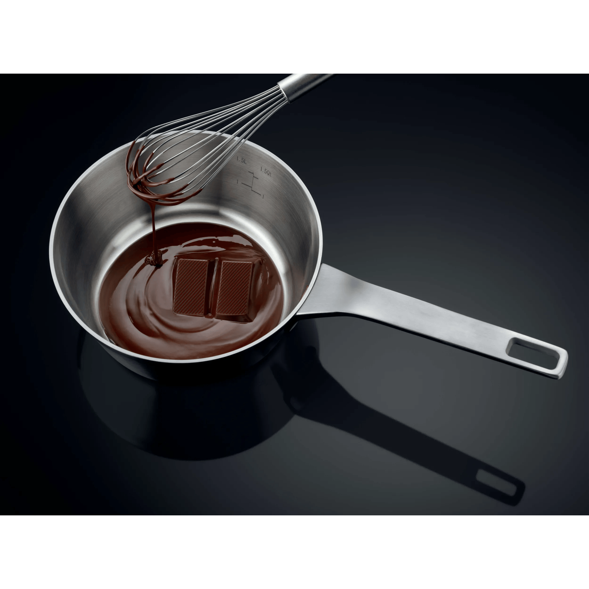 Una frusta gocciola cioccolato fuso in una pentola con due pezzi di cioccolato.