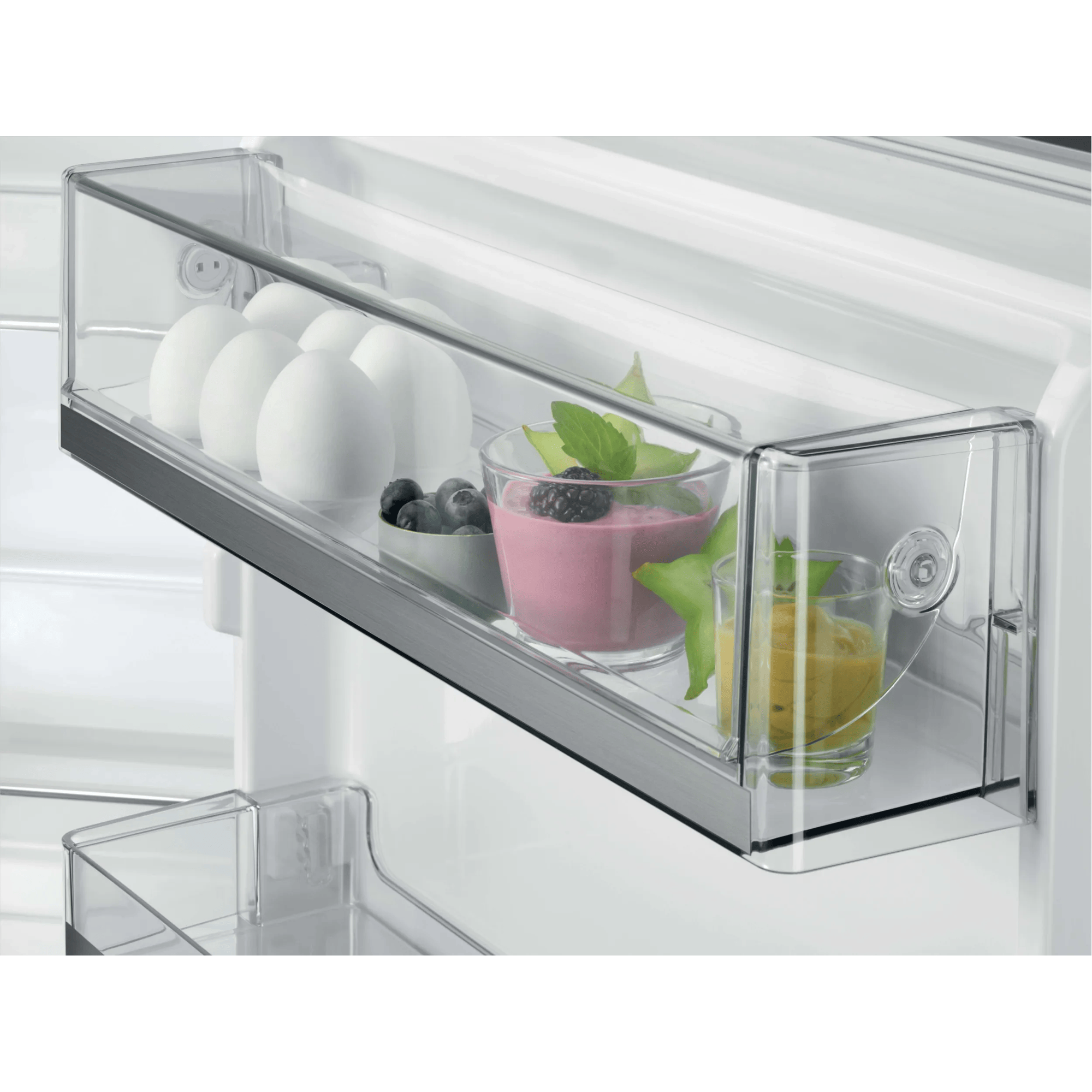 Cajón transparente en frigorífico con huevos, arándanos, batido rosa y puré amarillo.