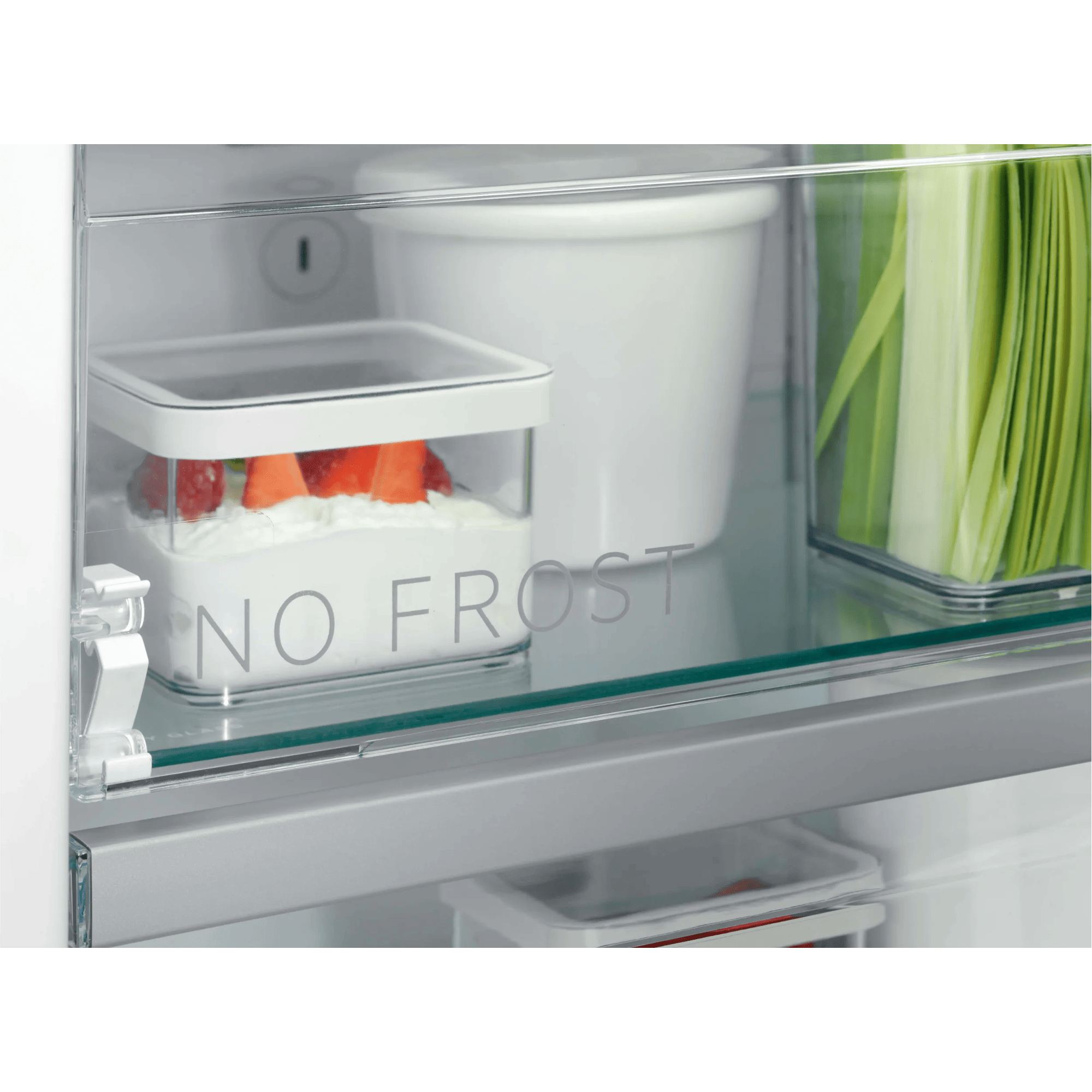 Un recipiente transparente con yogur y fresas dentro de un refrigerador.