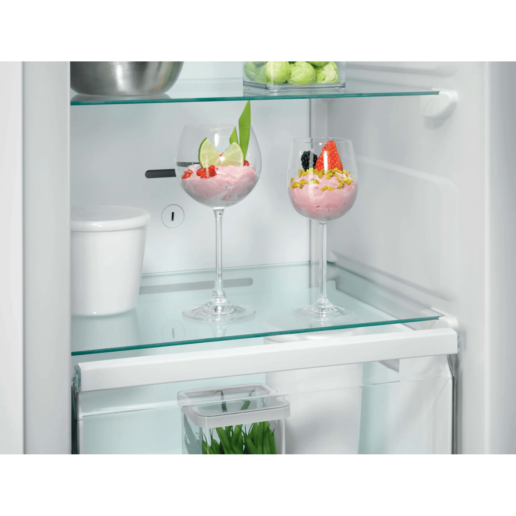 Dos copas con postre rosa, adornadas con frutas y menta.