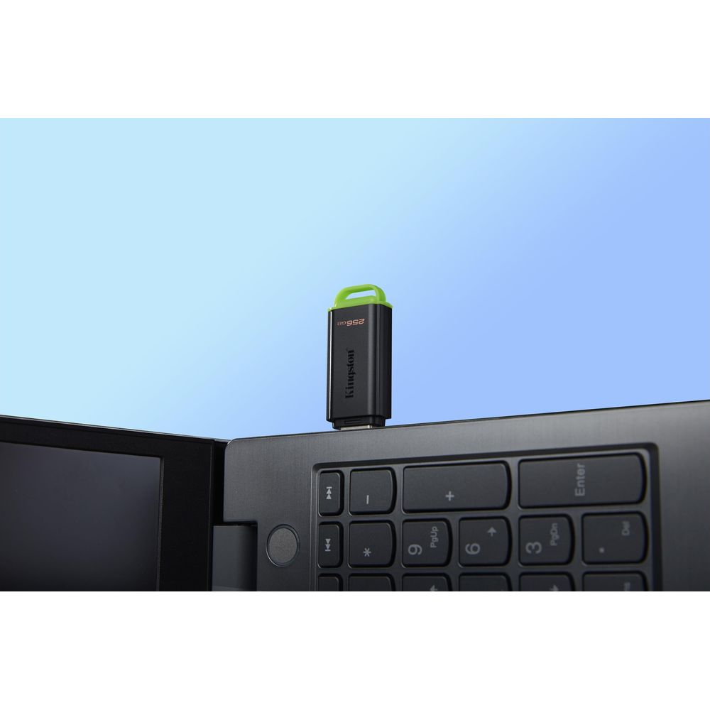 Czarny pendrive Kingston z zieloną pętlą na klawiaturze laptopa.