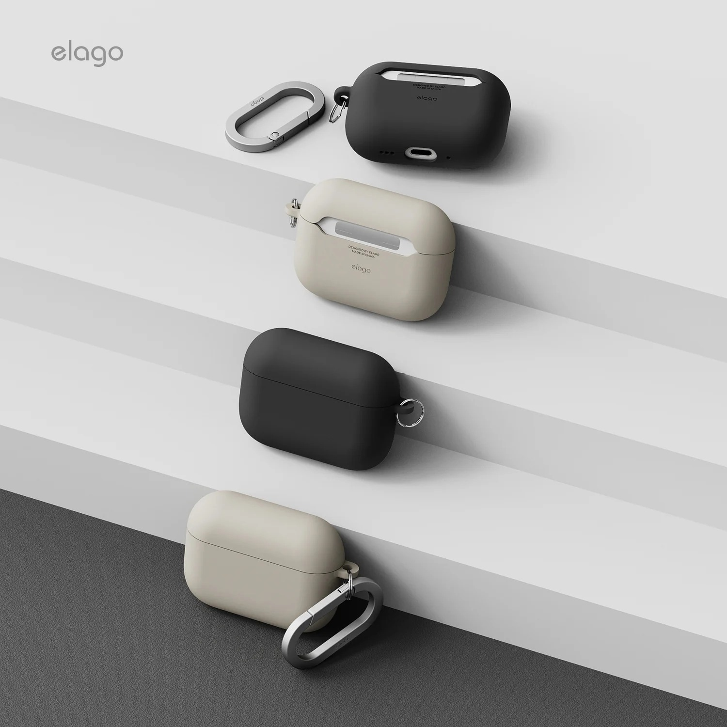 Cztery czarne i beżowe etui na AirPods z karabińczykami na szarej i białej stopniowanej powierzchni.