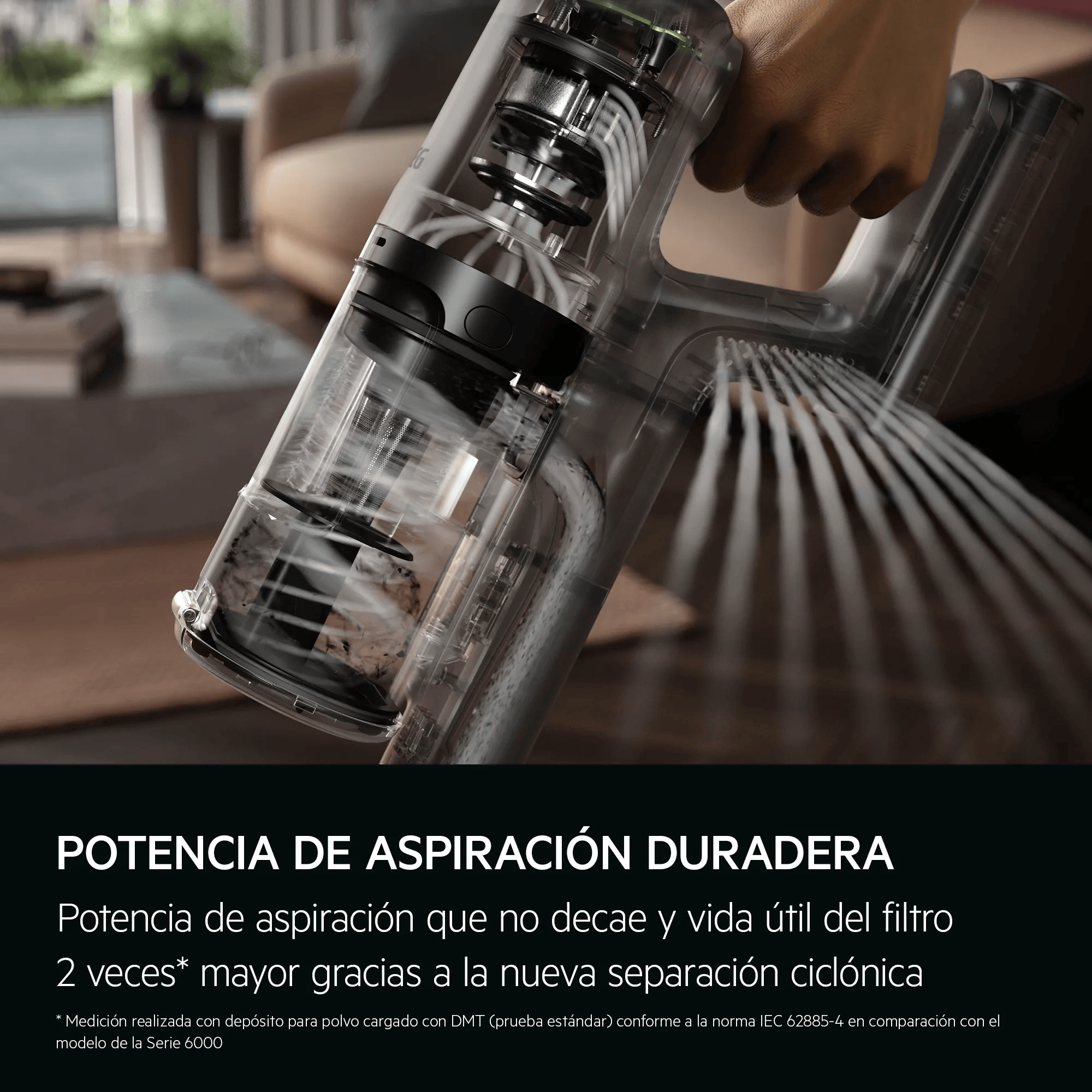 Mano sostiene aspiradora transparente, succionando polvo. Componentes internos visibles.