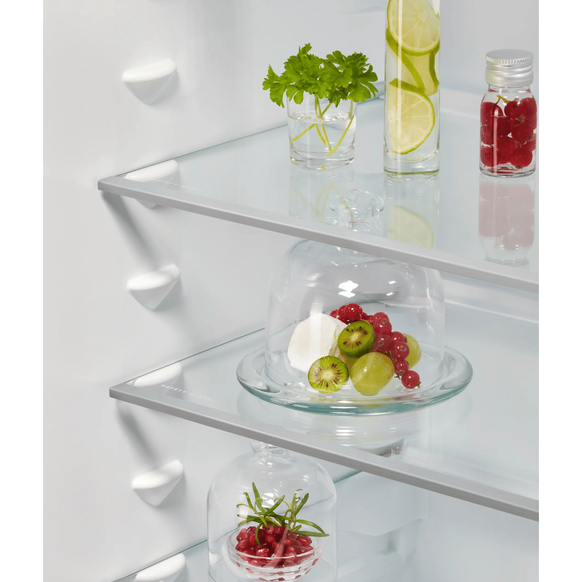 Estantes de refrigerador con frutas y hierbas en recipientes de vidrio.