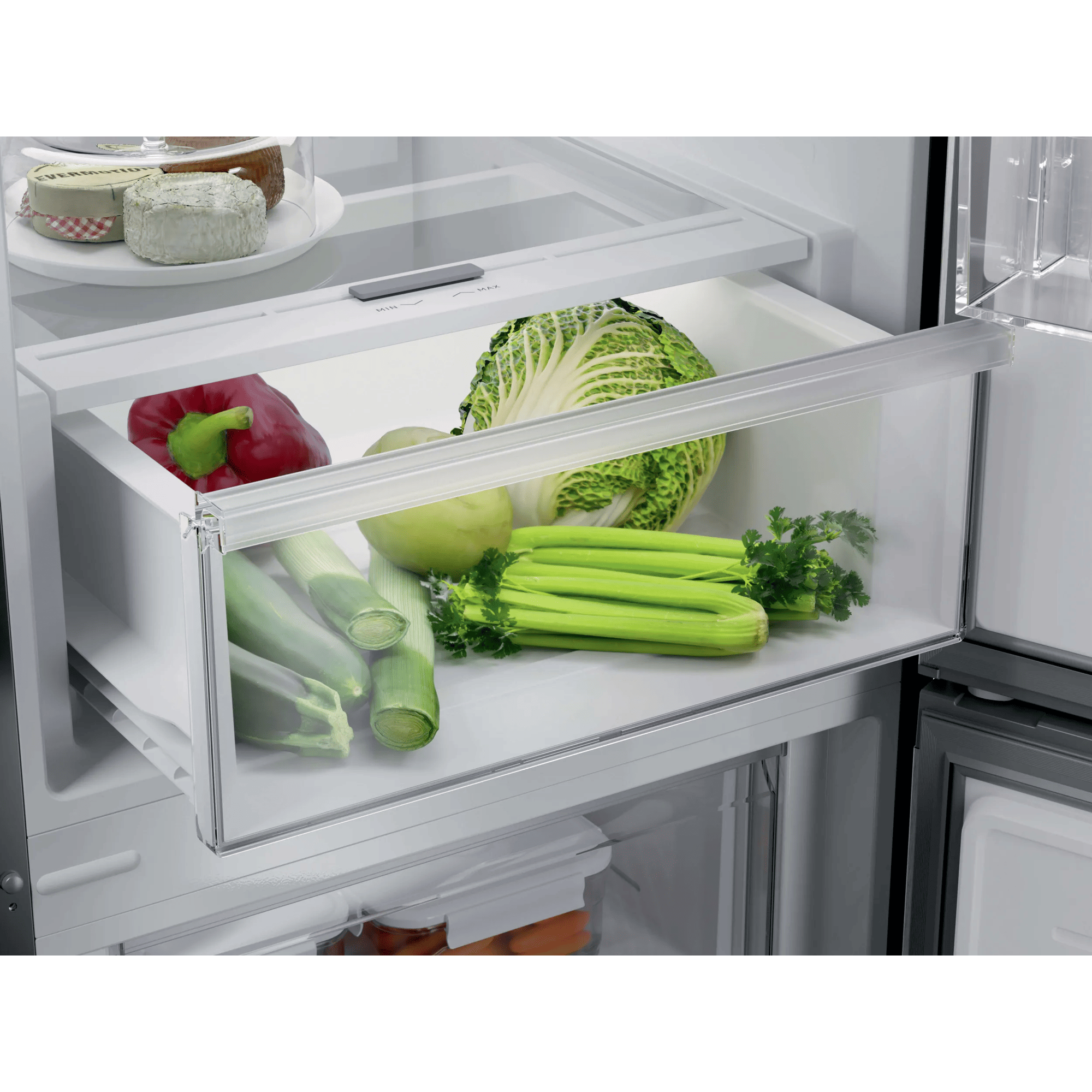Un cajón de refrigerador con col roja, zanahorias, apio, puerros, pimiento y manzana.