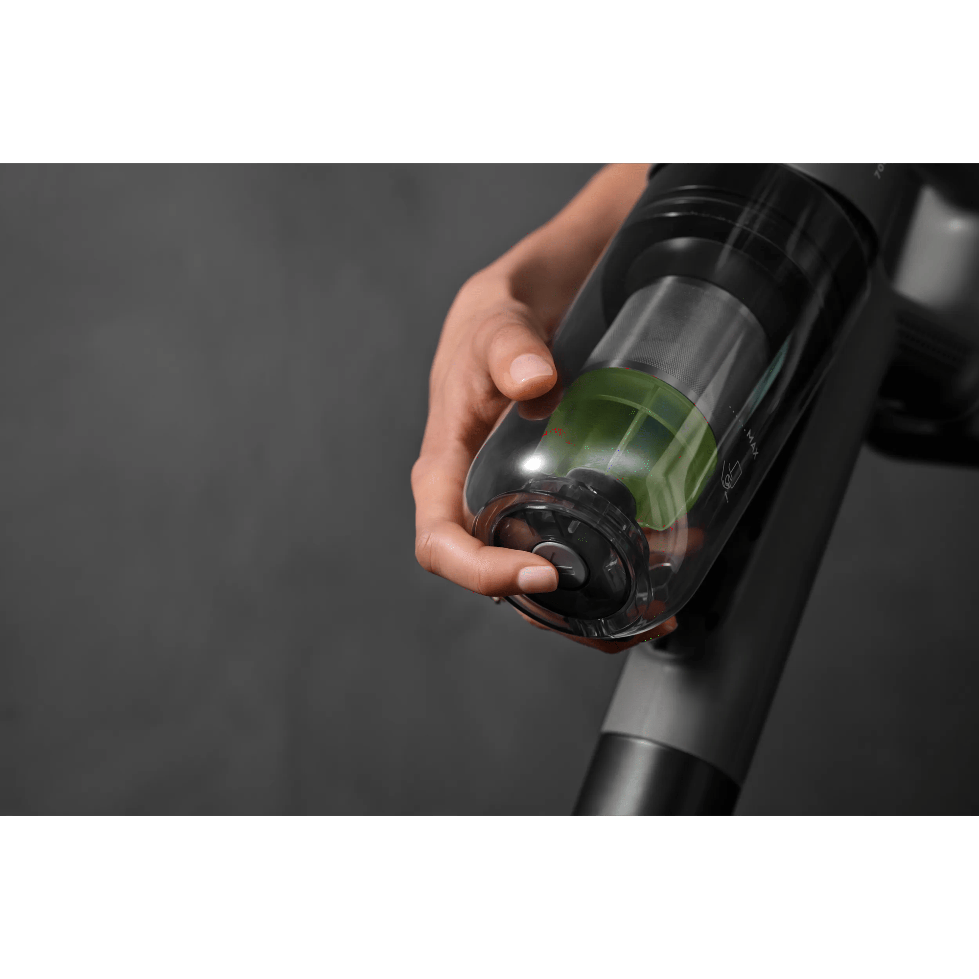 A hand holds a clear container with green contents and a button.