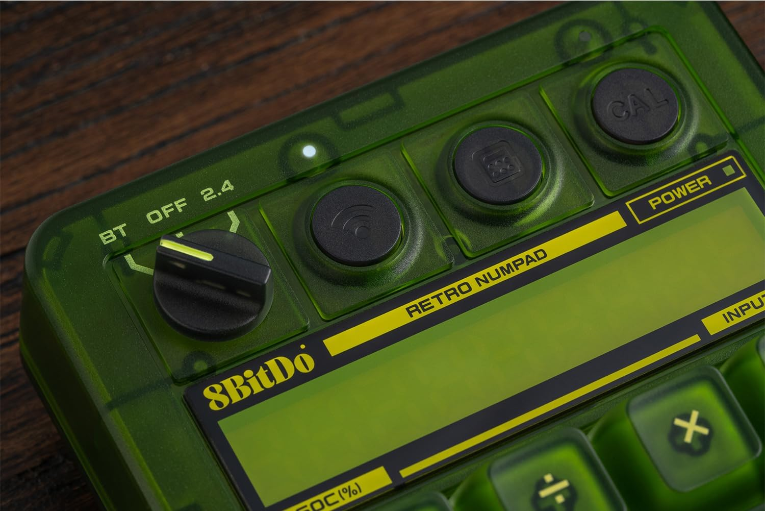 Zielony retro numpad z pokrętłem, przyciskami i ekranem LCD na drewnianym tle.