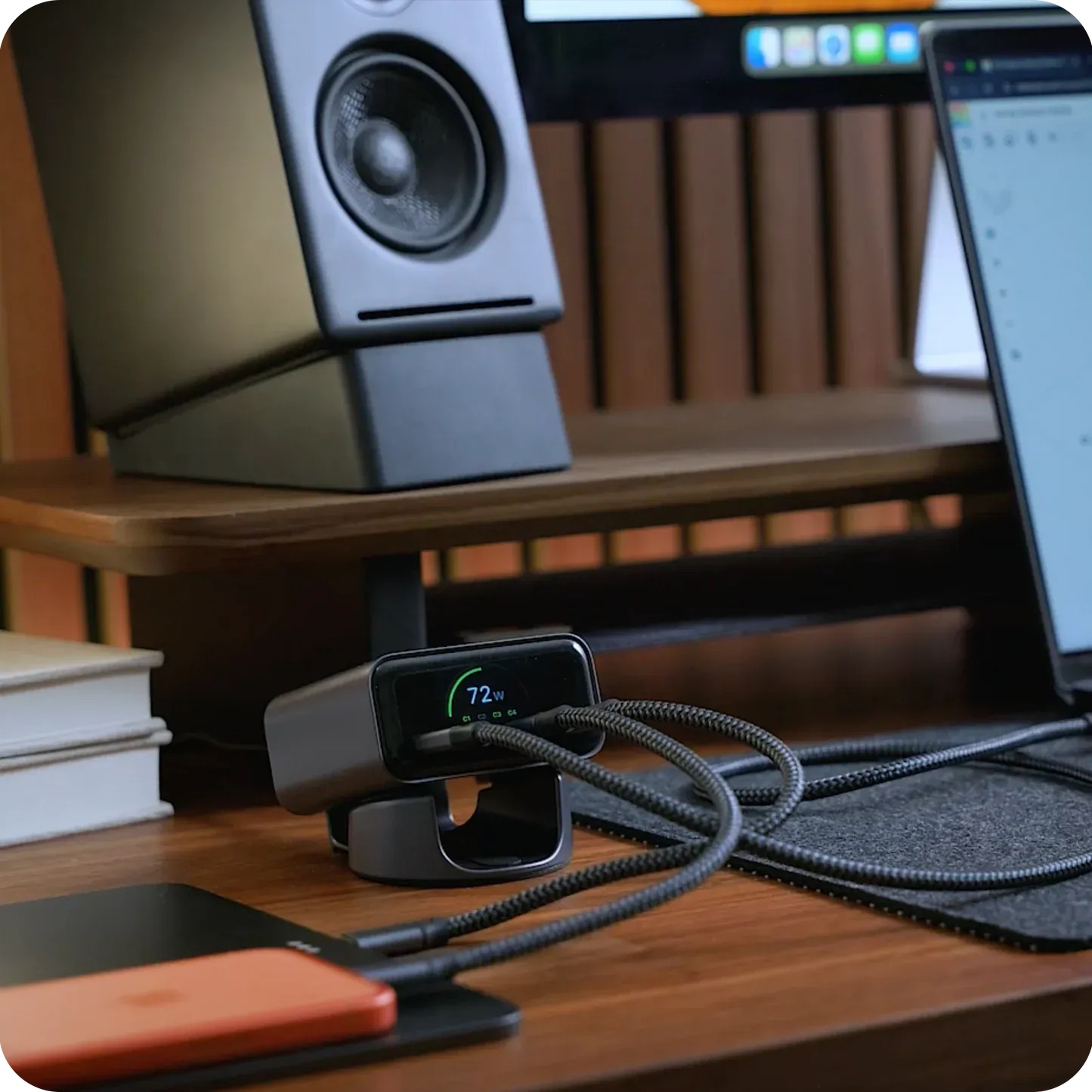 Un hub di ricarica nero con display da 72W è su una scrivania di legno con cavi.