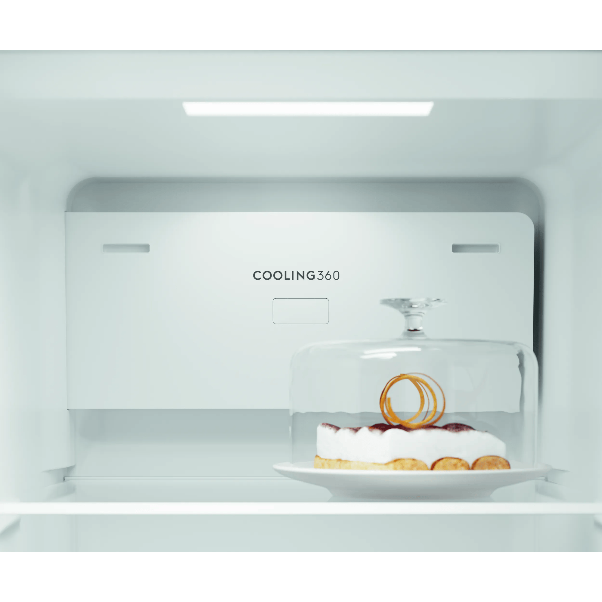 Un pastel bajo una campana de cristal dentro de un refrigerador.
