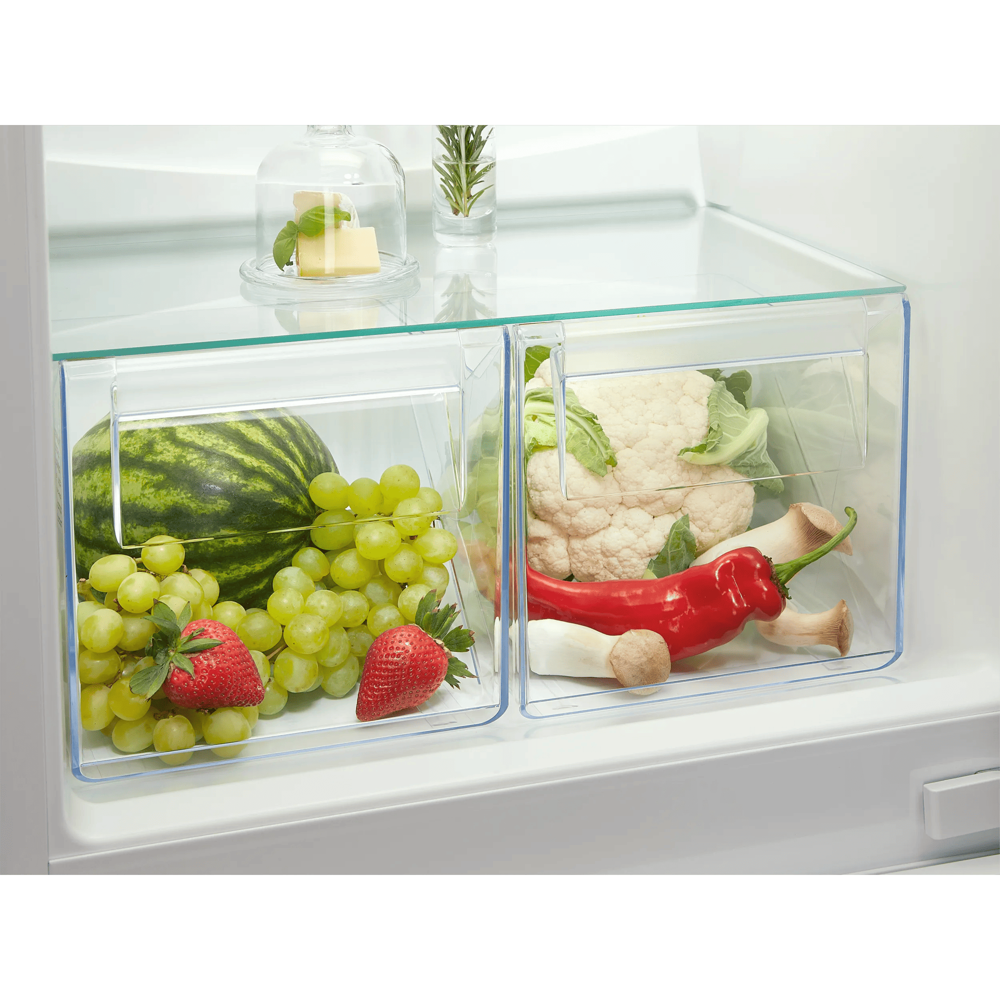 Frutas y verduras frescas en cajones del refrigerador: sandía, uvas, fresas, coliflor, pimientos.