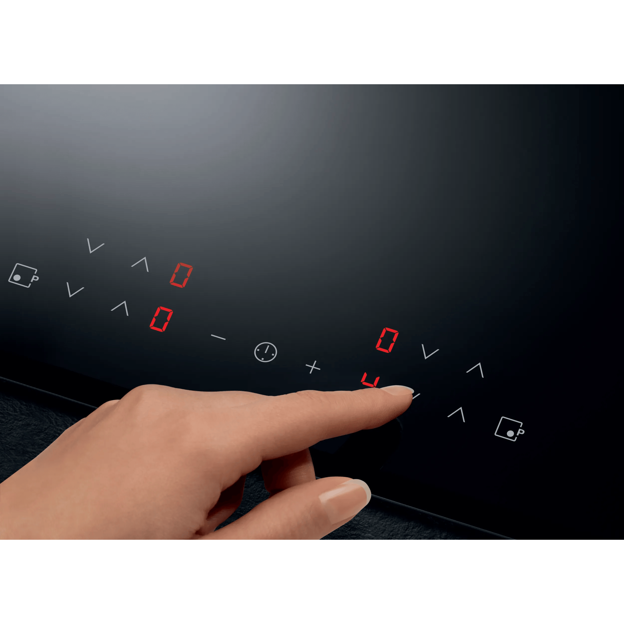 Una mano tocca il pannello di controllo di un piano cottura a induzione nero con display digitali rossi.