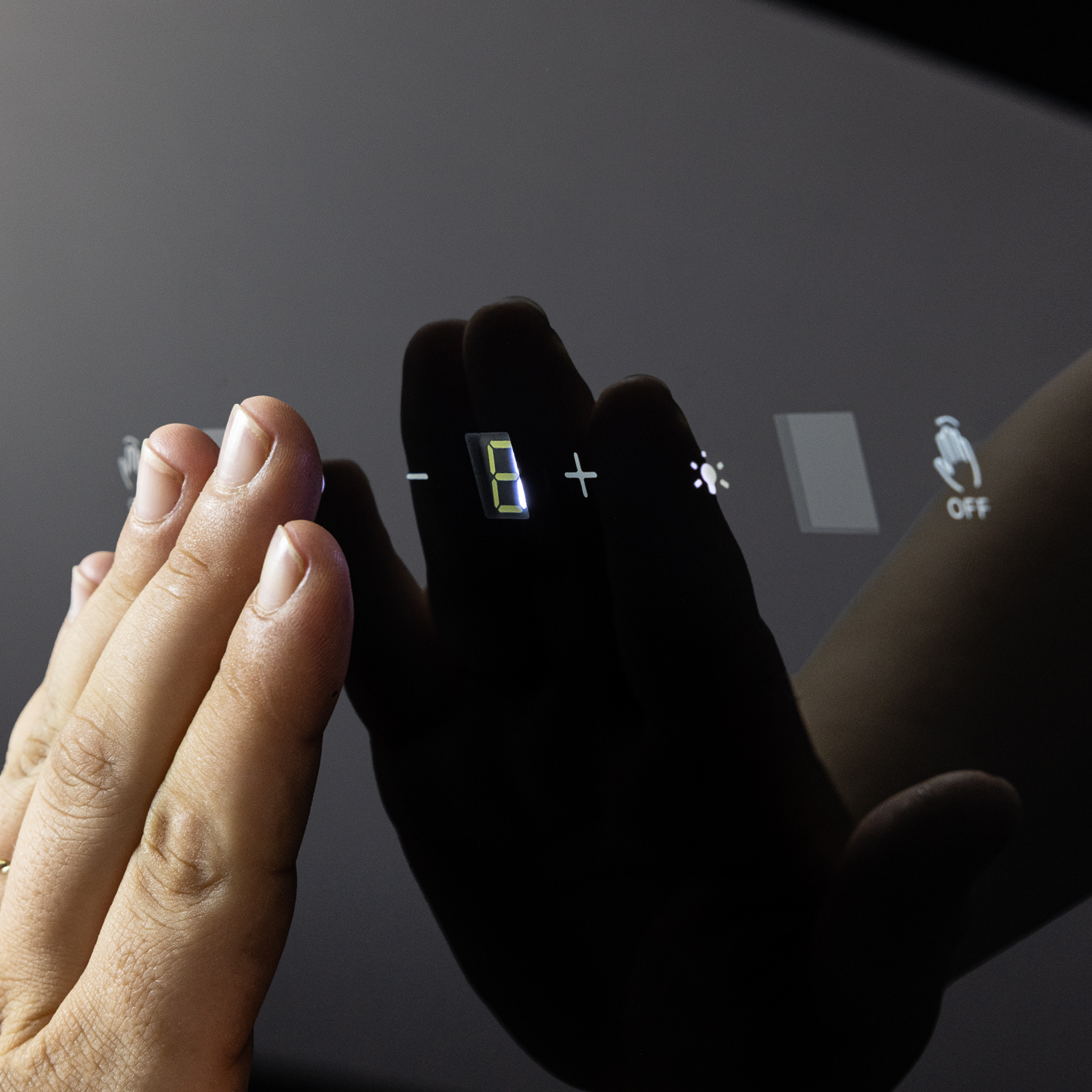Una mano tocca un touch screen scuro con controlli illuminati.