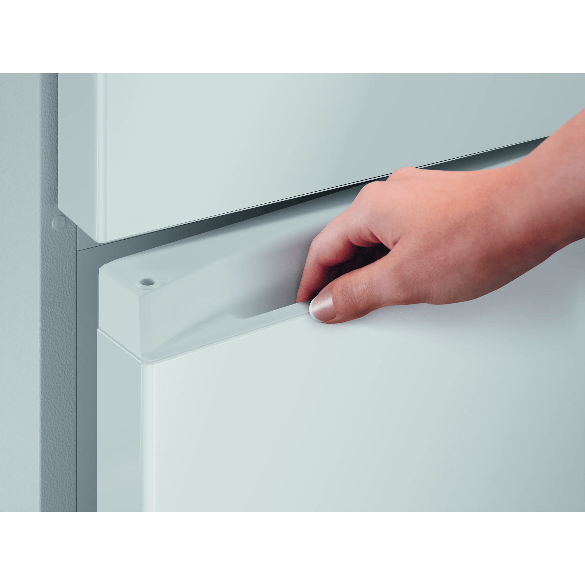 Una mano alcanza el tirador del cajón de un refrigerador.