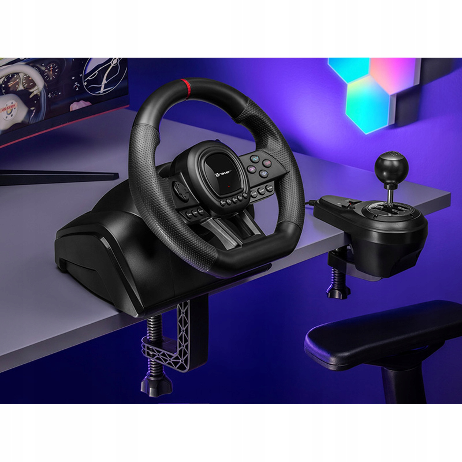 Un volante da corsa nero e un cambio sono montati su una scrivania. Un monitor mostra una gara d'auto.
