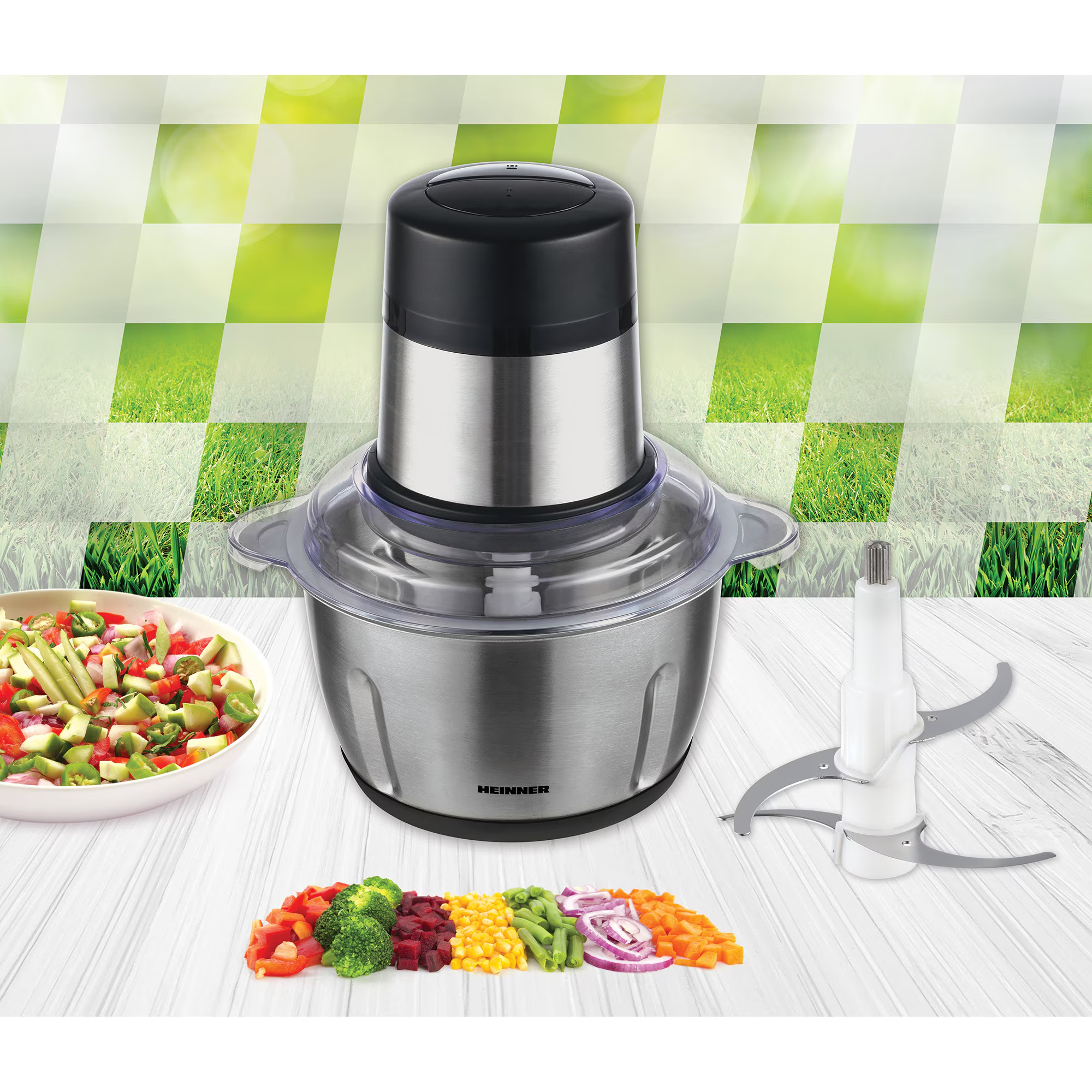 Un hachoir alimentaire avec bol en acier inoxydable, oignons, carottes, brocolis, maïs, haricots et salade.