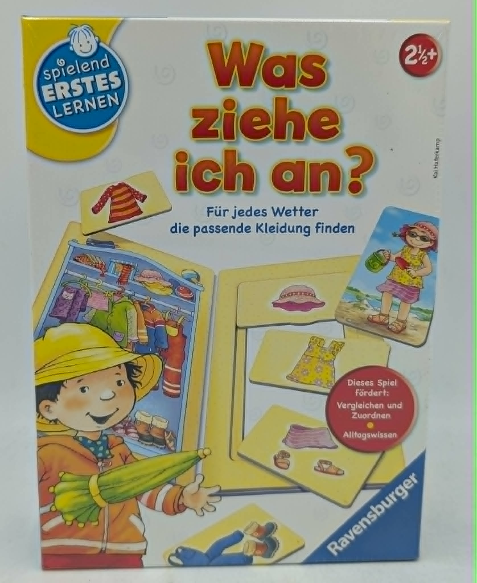 Brettspiel: Junge mit Regenjacke und Schirm vor Kleiderschrank.