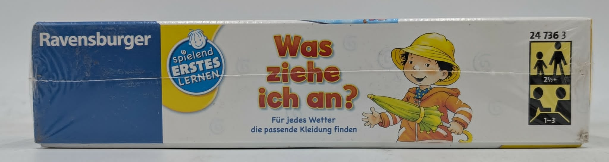 Ravensburger Spiel: Was ziehe ich an? Kind mit Regenschirm und gelber Regenkleidung.