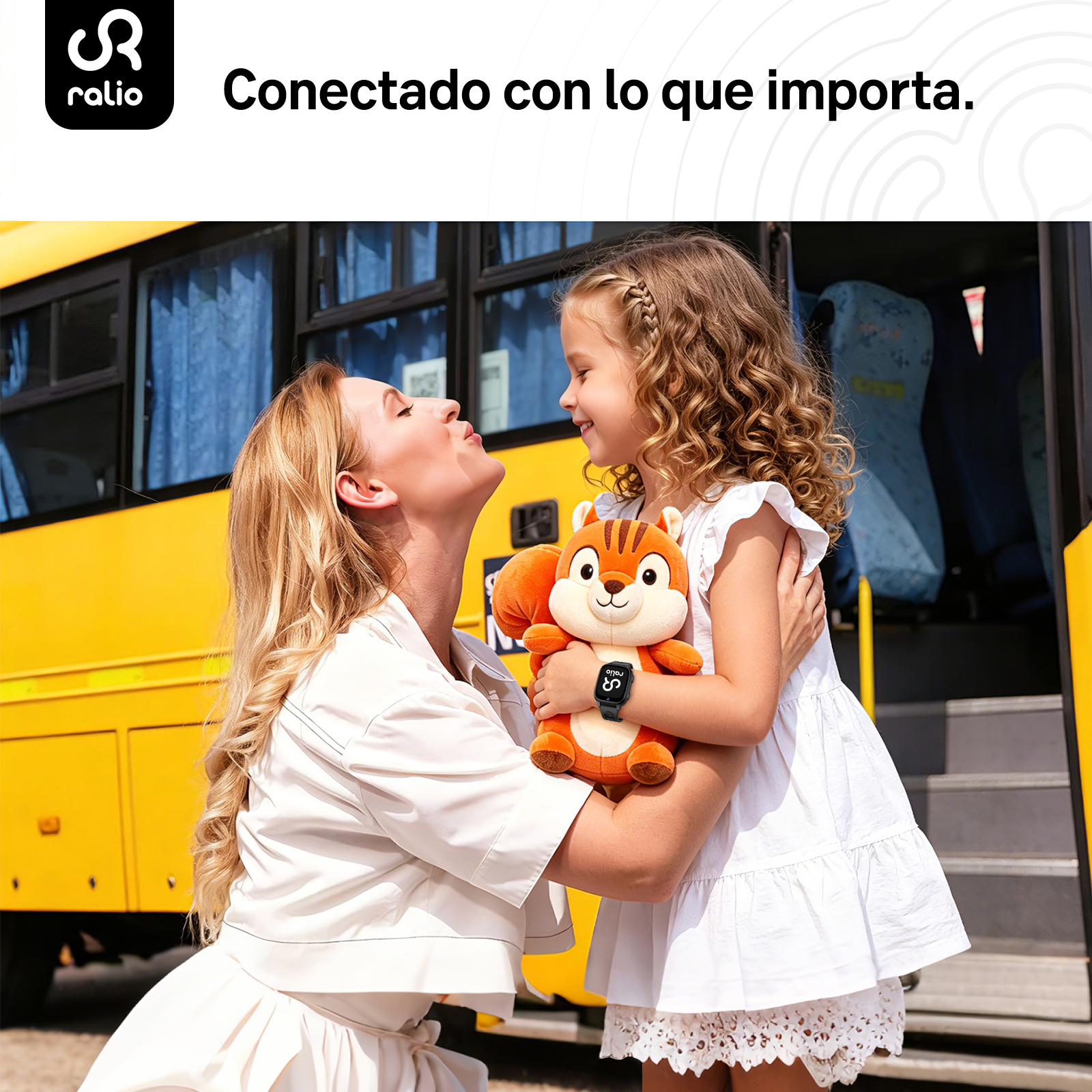 Una mujer y un niño se abrazan frente a un autobús escolar amarillo. Sostienen un peluche de ardilla.