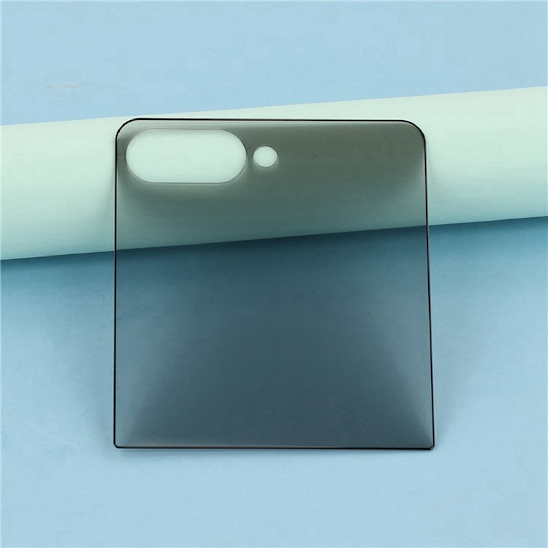 Copertura fotocamera in vetro grigio scuro con due ritagli per obiettivi su sfondo chiaro.