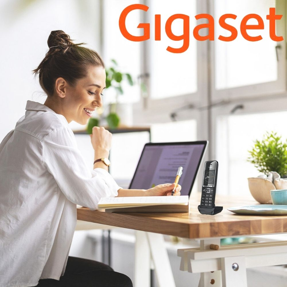 Kobieta pracuje przy laptopie, obok telefon Gigaset, w biurze.