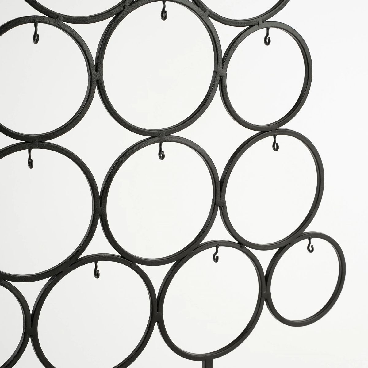 Een zwart metalen frame met ringen en haken tegen een witte achtergrond.