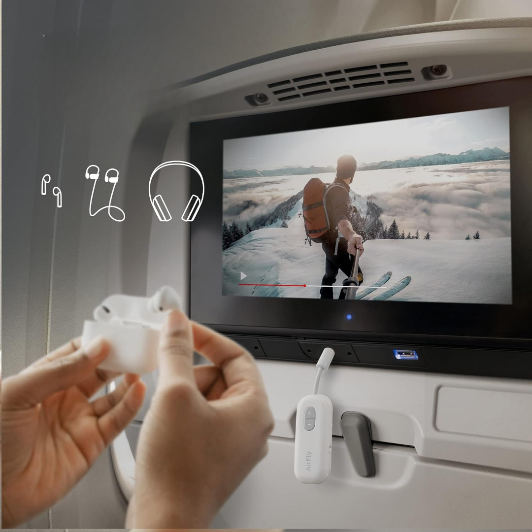 Hände halten weiße Ohrhörer vor einem Flugzeugbildschirm mit einem Skifahrer.