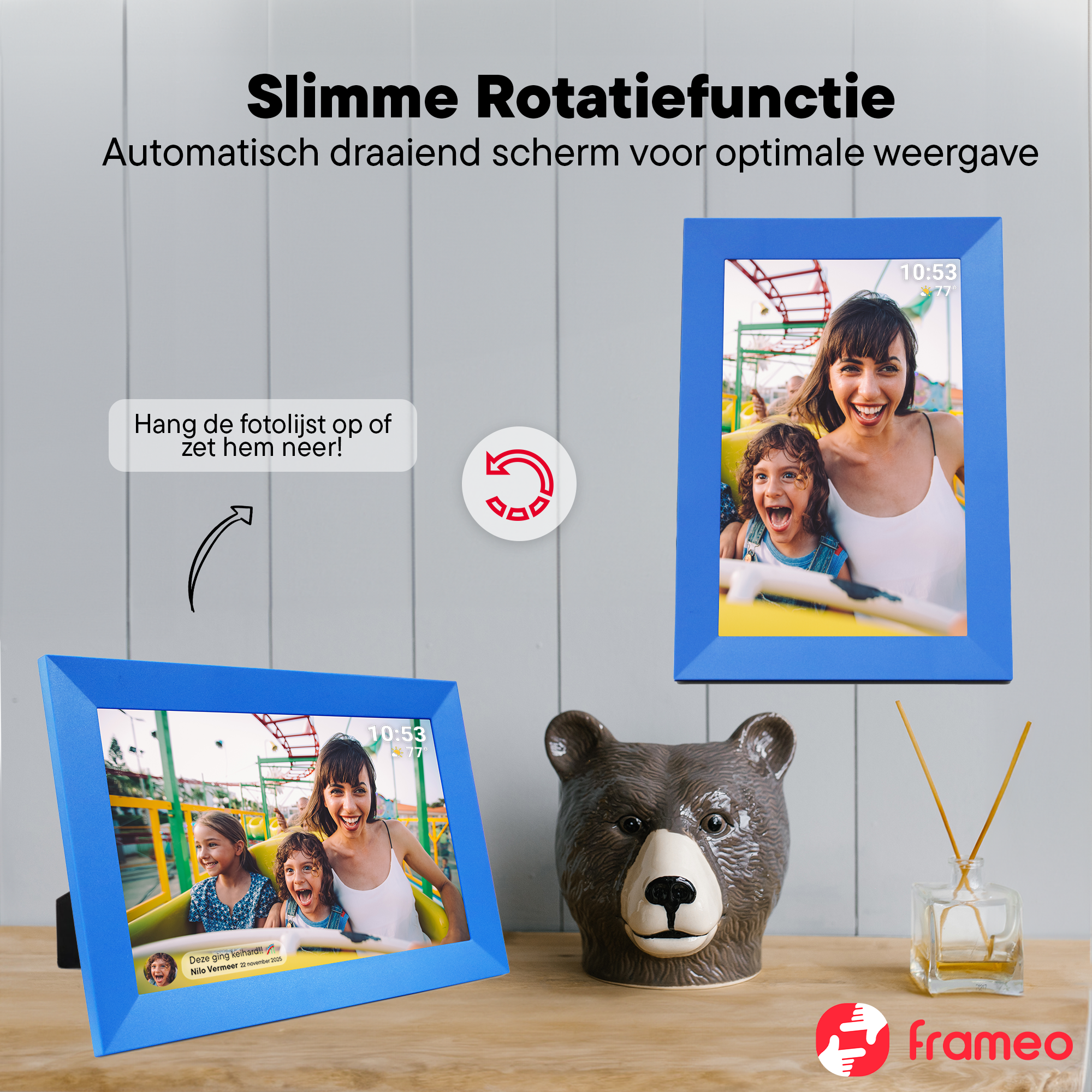 Two blue digital picture frames on a wooden table, next to bear ceramic and diffuser.