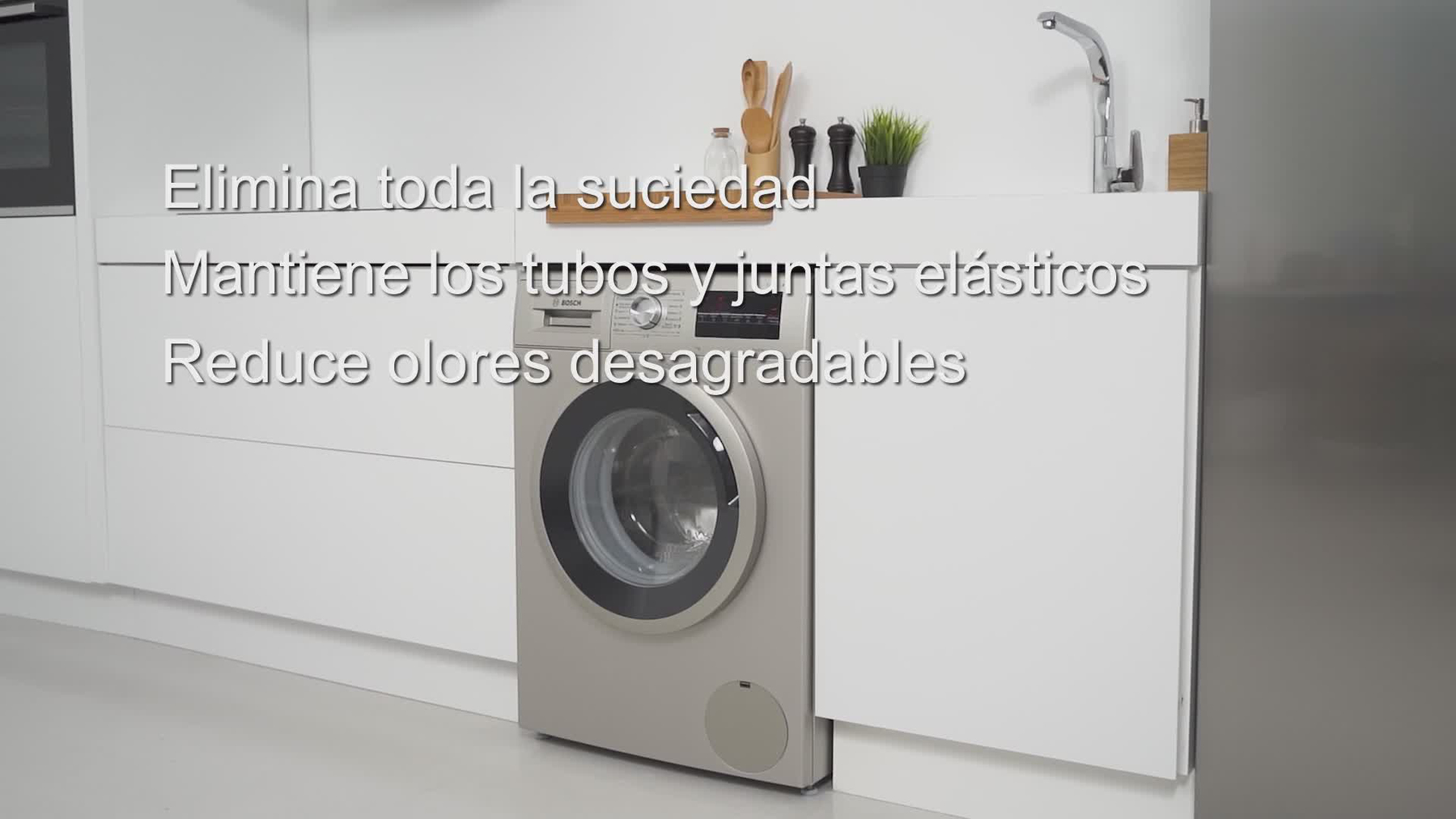 Una lavatrice si trova in una cucina moderna accanto ad armadi bianchi.