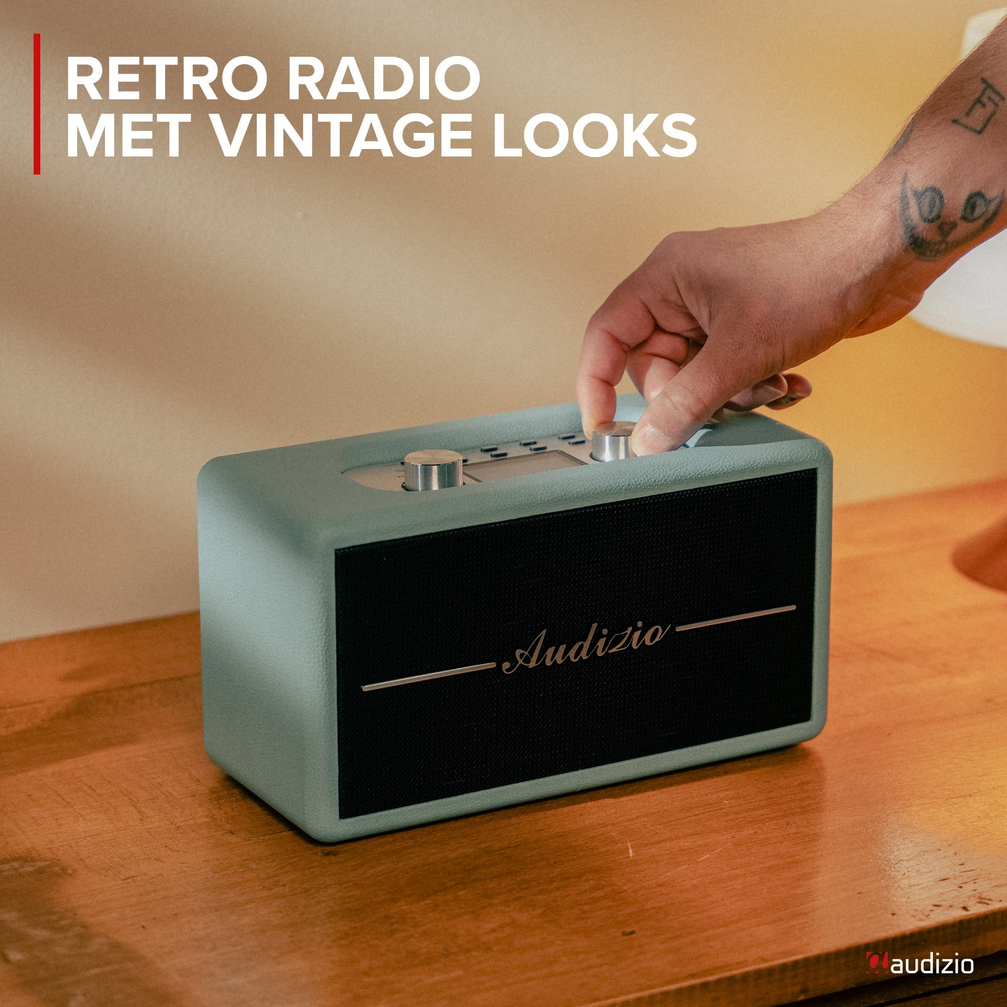 Un hombre ajusta una radio retro verde menta sobre una mesa de madera.
