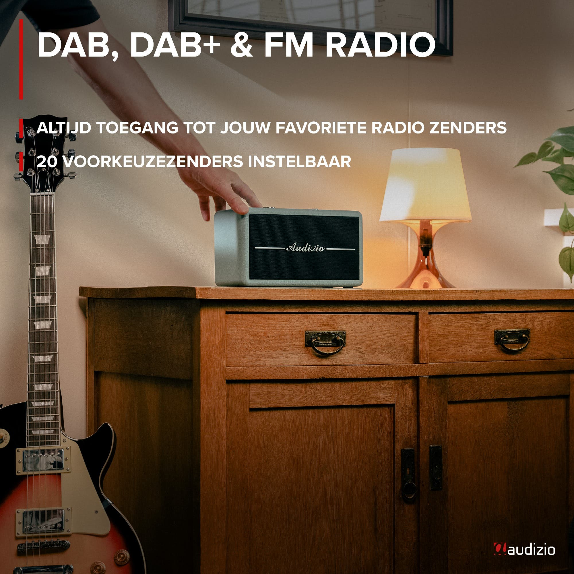 Un hombre coloca una radio Audizio gris en una cómoda de madera junto a una guitarra y una lámpara.