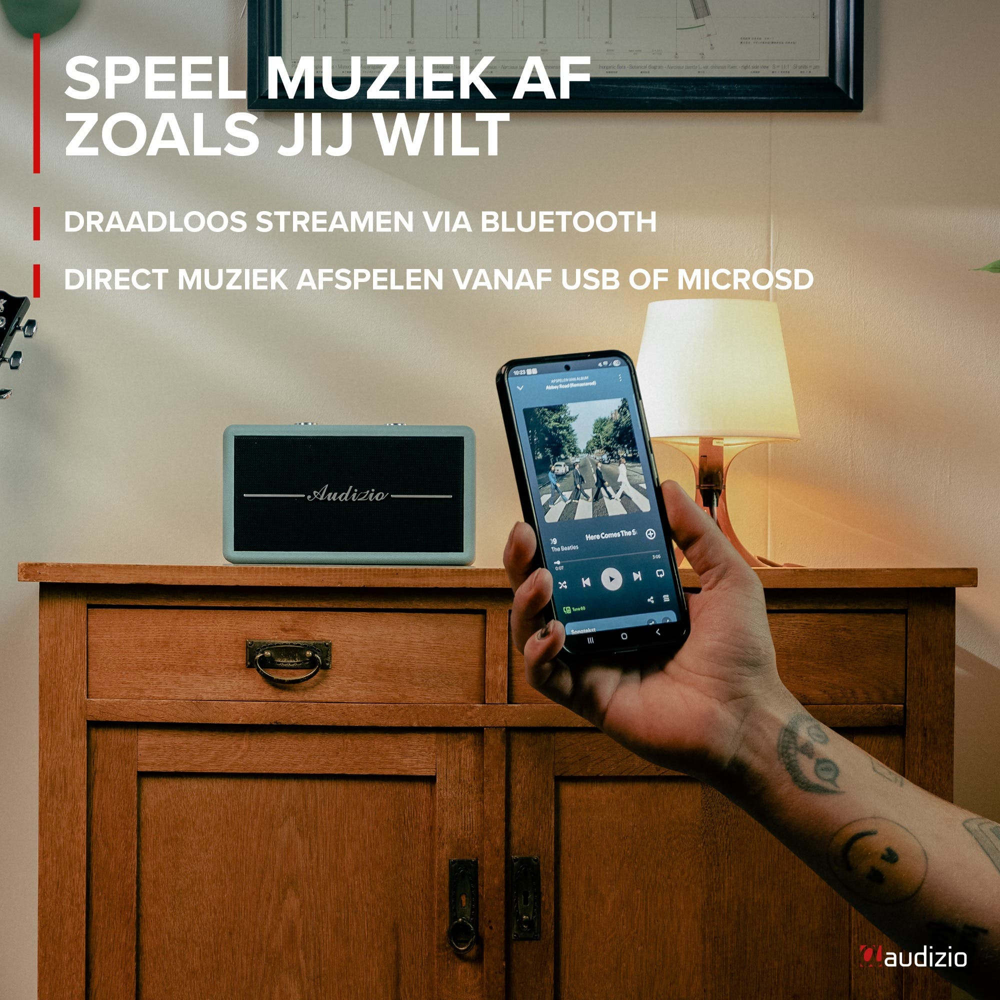 Una persona sostiene un smartphone reproduciendo música junto a un altavoz azul.