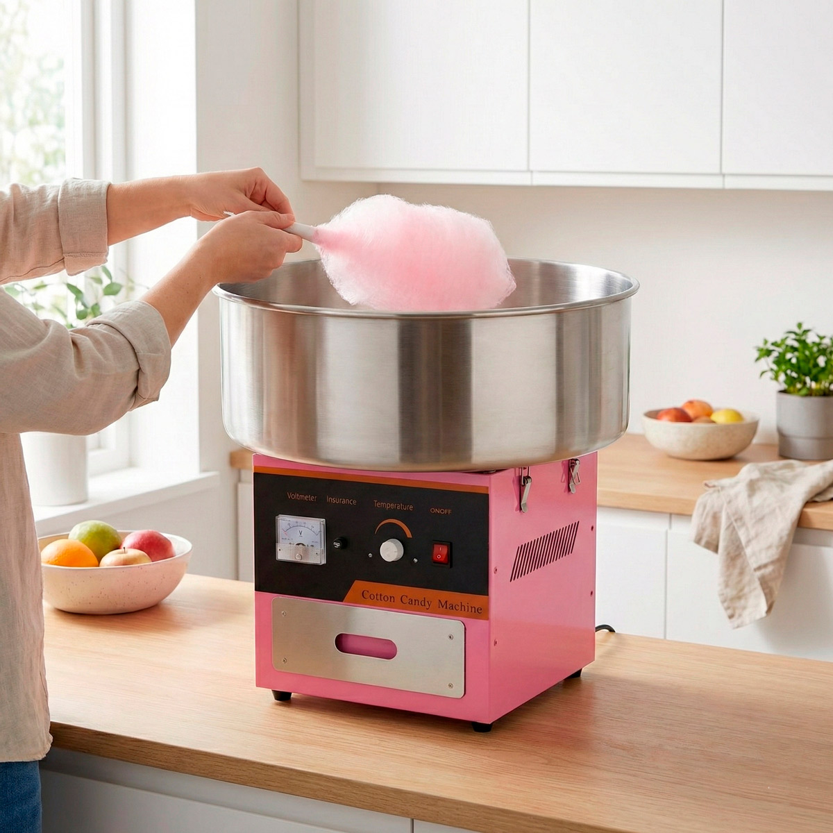 Eine Person macht Zuckerwatte auf einer pinken Maschine in einer Küche.