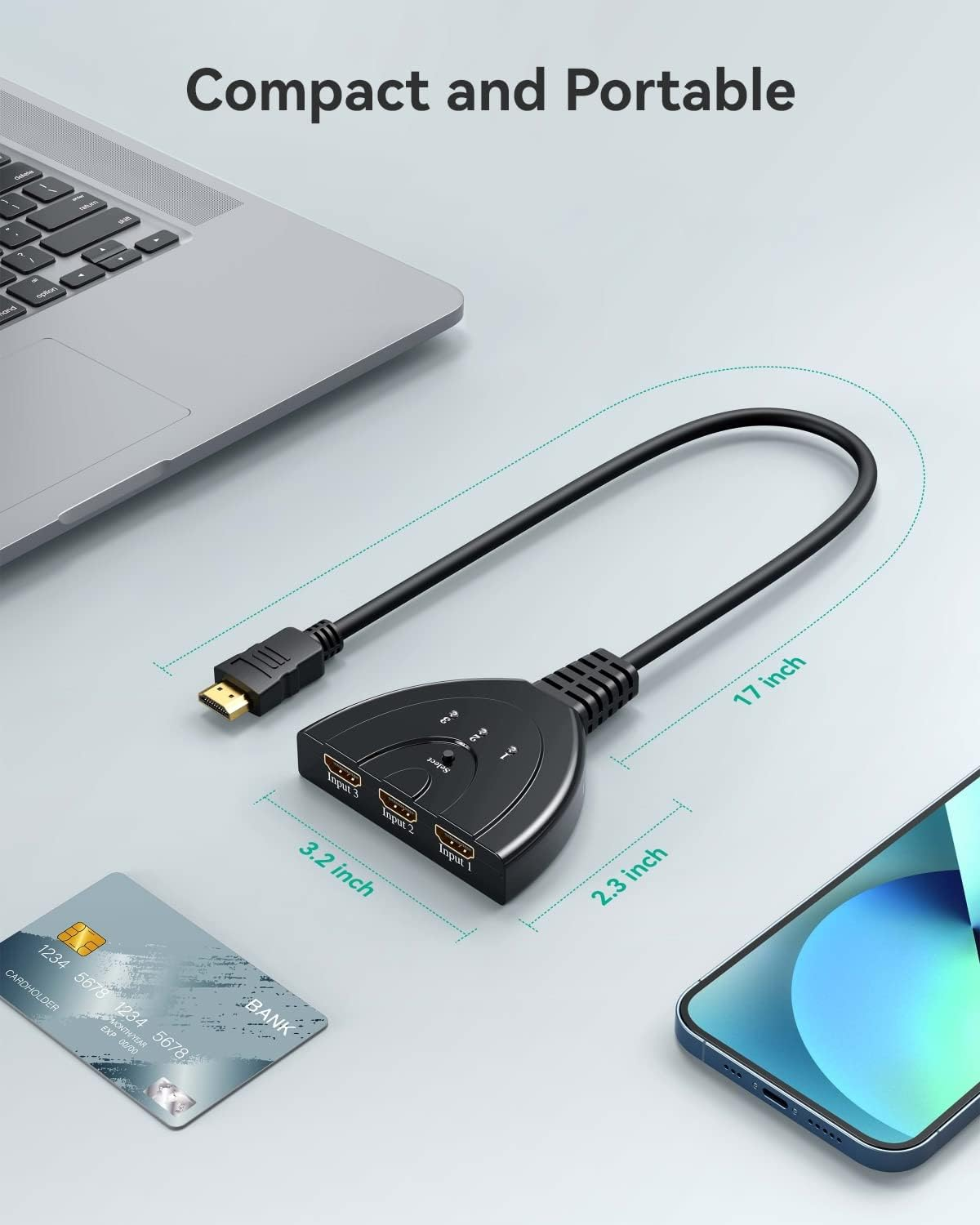 Schwarzer HDMI-Switch mit Kabel, neben Laptop, Kreditkarte und Smartphone.