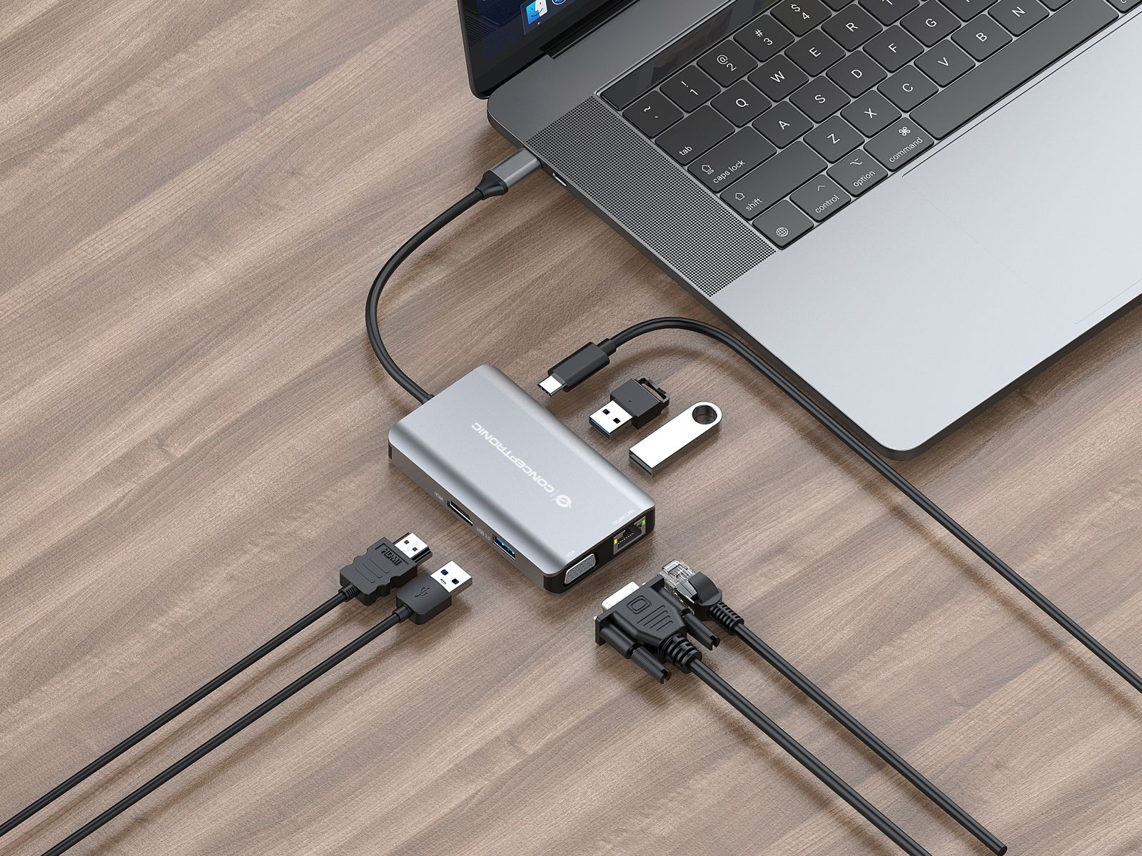 Un hub USB-C argentato con cavi e porte si trova accanto a un laptop.