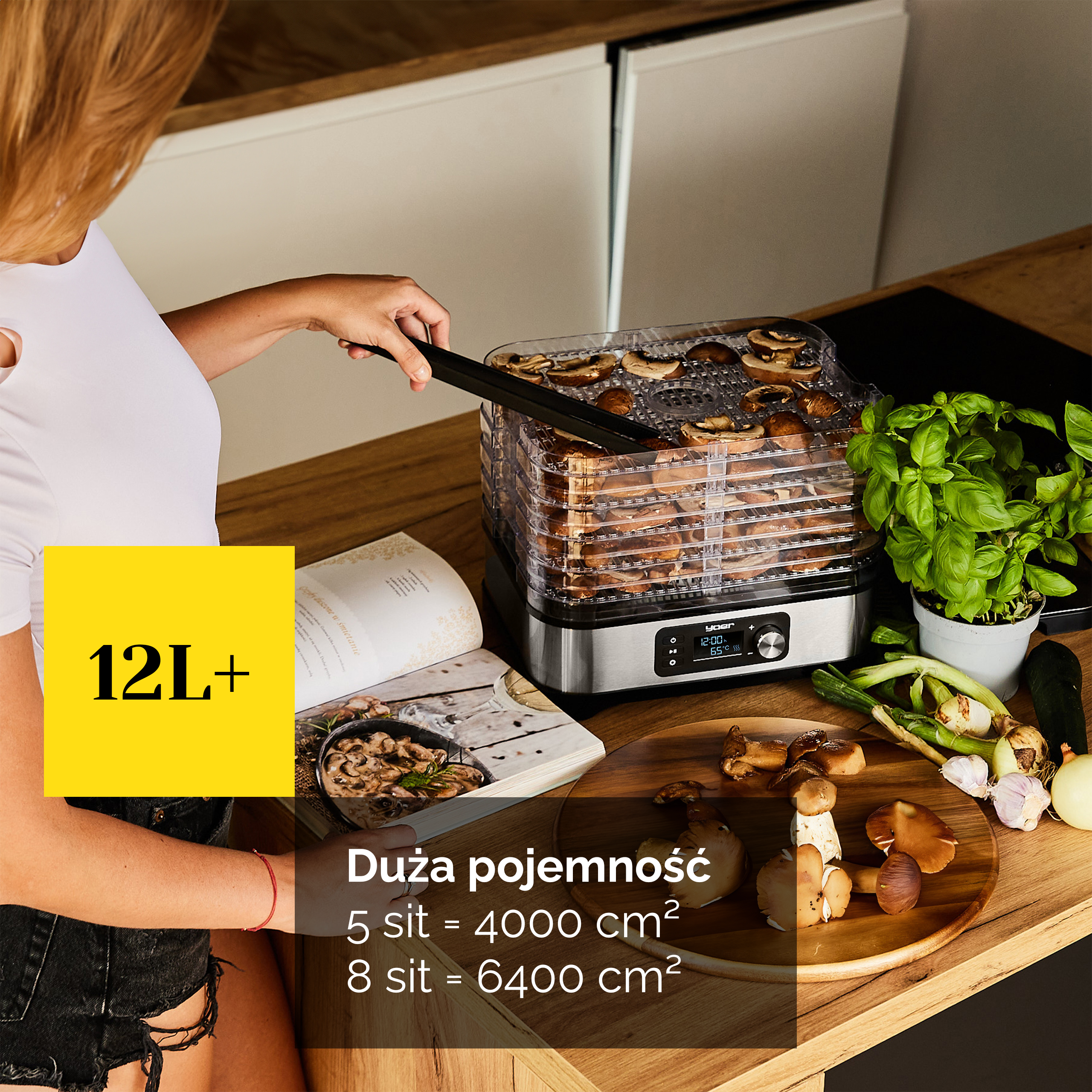 Kobieta używa suszarki do żywności z grzybami. Obok książka kucharska i świeże warzywa.