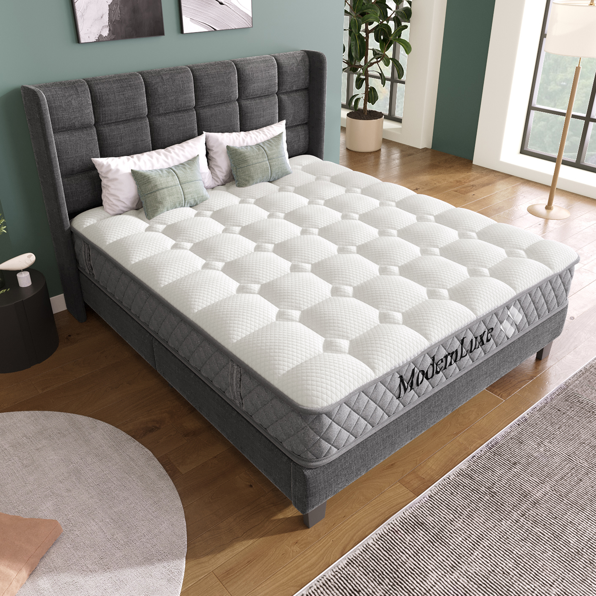 Ein weißes Bett mit gesteppter Matratze und grauem Kopfteil, daneben ein Nachttisch.