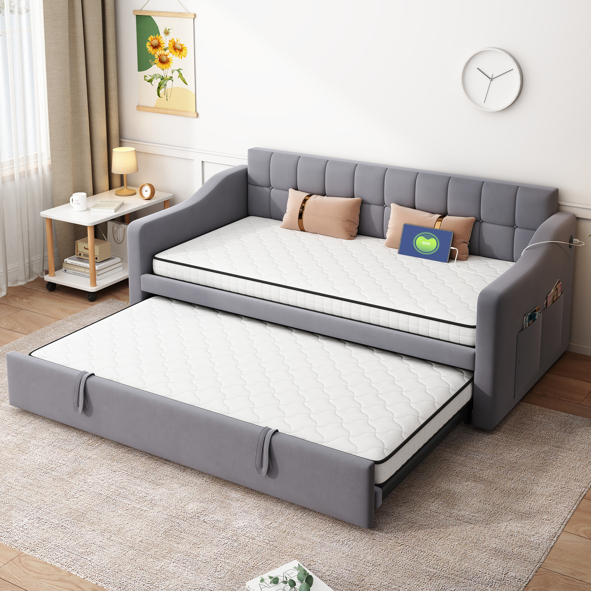 Graues Schlafsofa mit ausziehbarem Bett, Kissen, Tablet und Nachttisch.