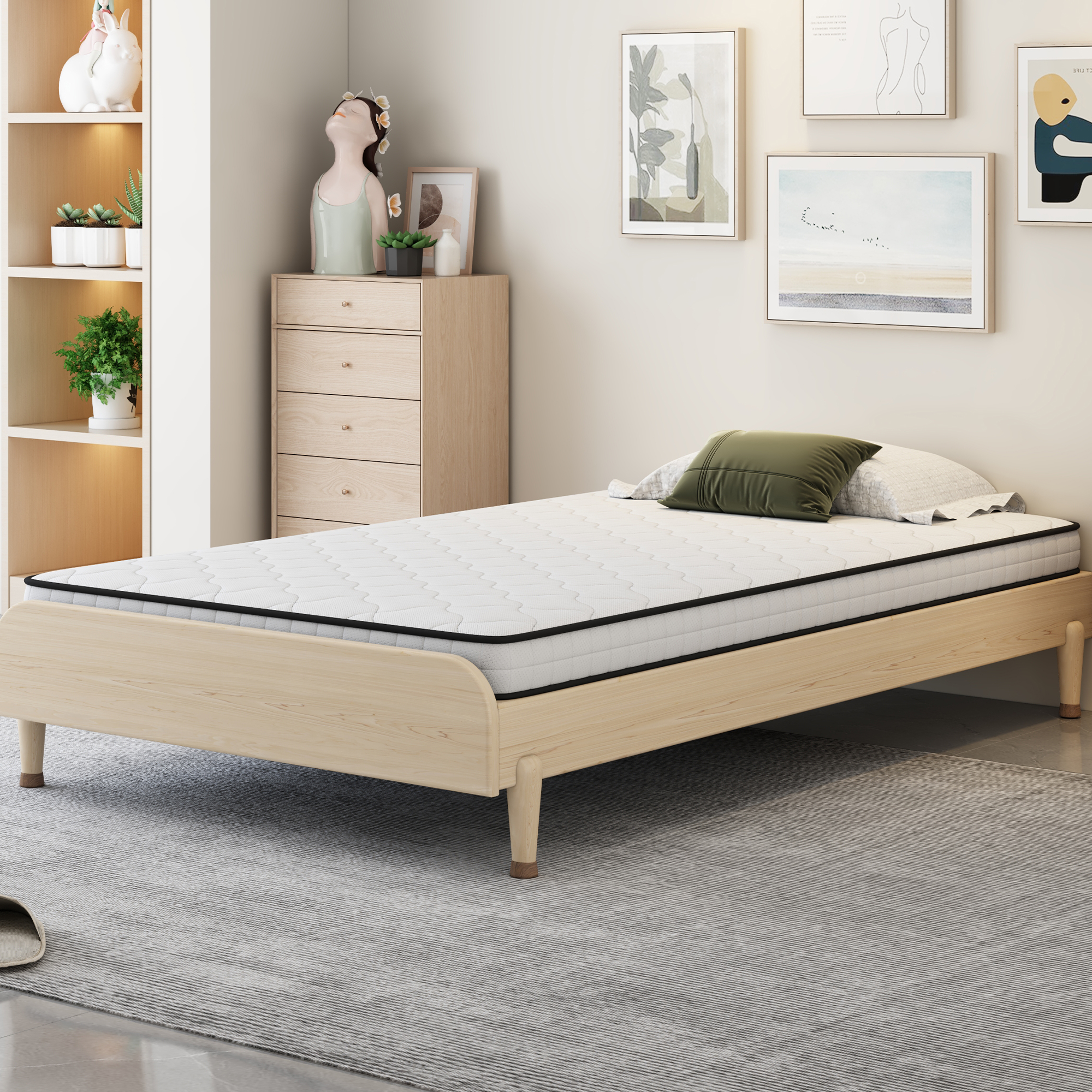 Ein Holzbett mit weißer Matratze und grünem Kissen in einem hellen Raum.