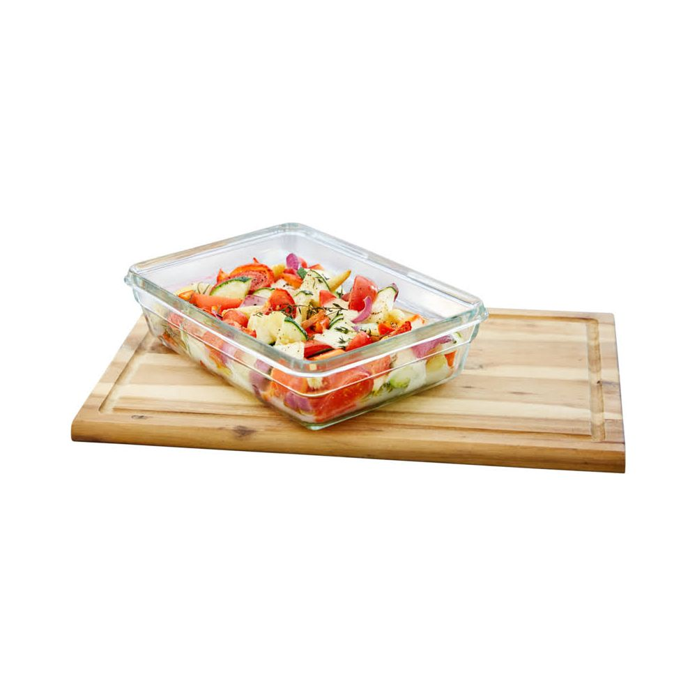 Ein Glasbehälter mit geschnittenem Gemüse wie Tomaten, Zwiebeln und Kartoffeln steht auf einem Holzbrett.