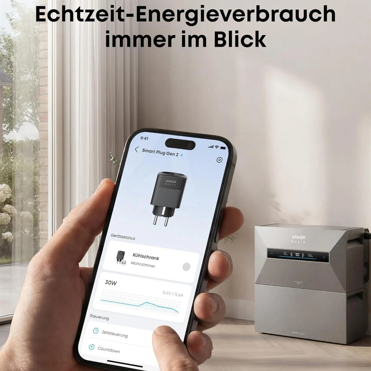 Een hand houdt een smartphone vast met een app voor koelkast energieverbruik. Een Anker Solix apparaat staat ernaast.