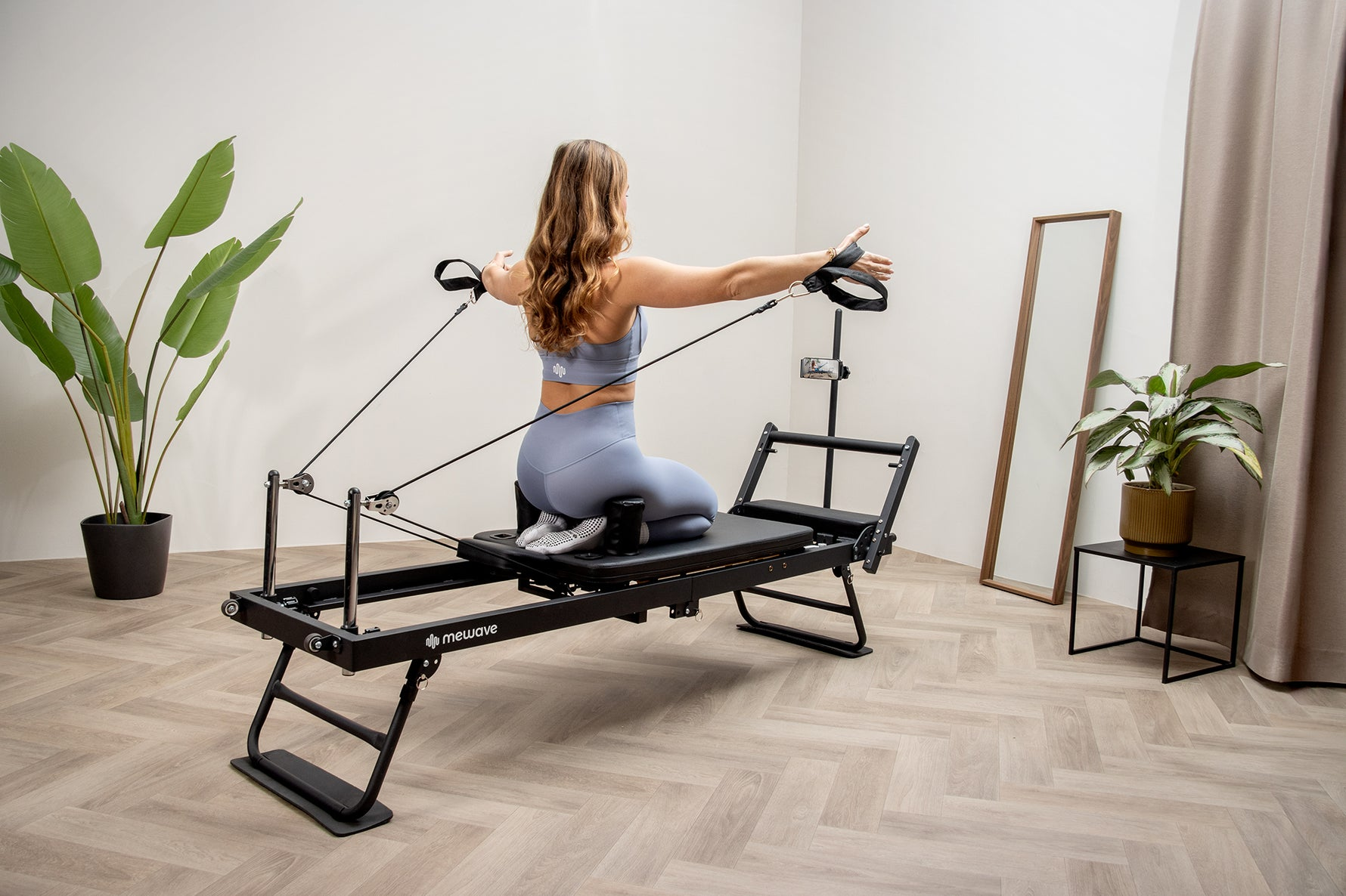 Mujer haciendo ejercicio en máquina de Pilates con cuerdas en sala luminosa.