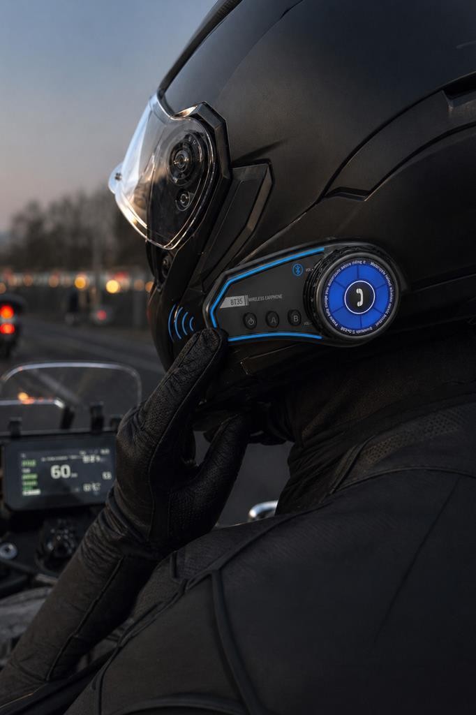 Mavi Bluetooth kulaklıklı siyah kask takan motosikletçi, gece sürüşü.