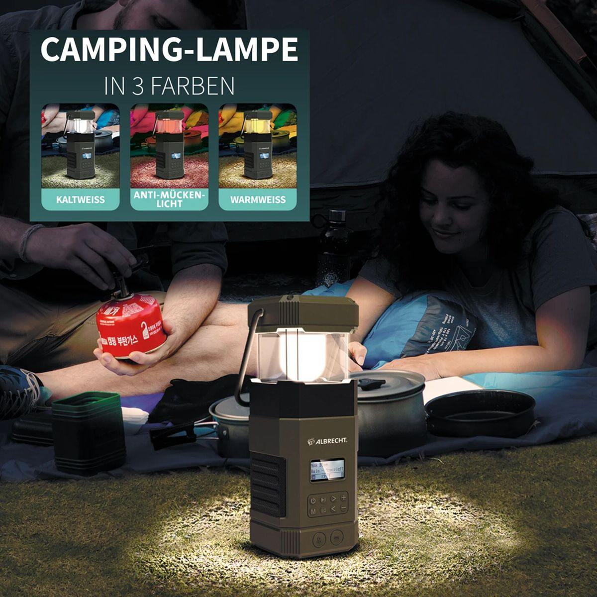 Campinglampe mit drei Lichtfarben leuchtet auf Gras, zwei Personen im Zelt.