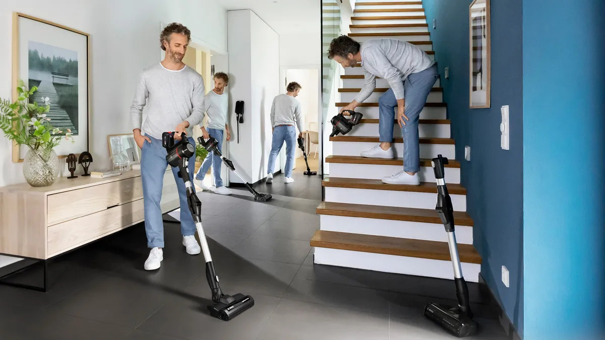 Uomo aspira scale e corridoio con aspirapolvere a batteria.