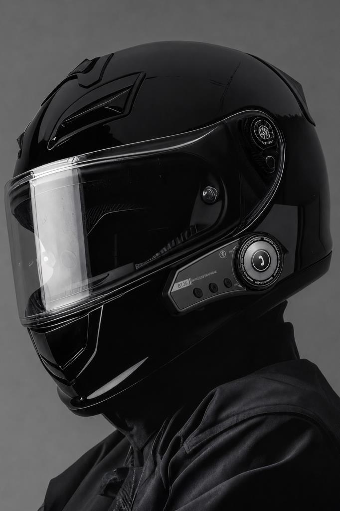 Şeffaf vizörlü ve Bluetooth kulaklıklı siyah motosiklet kaskı. Yan görünüm.