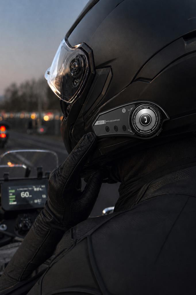 Alacakaranlıkta Bluetooth kulaklıklı kask takan motosikletçi.