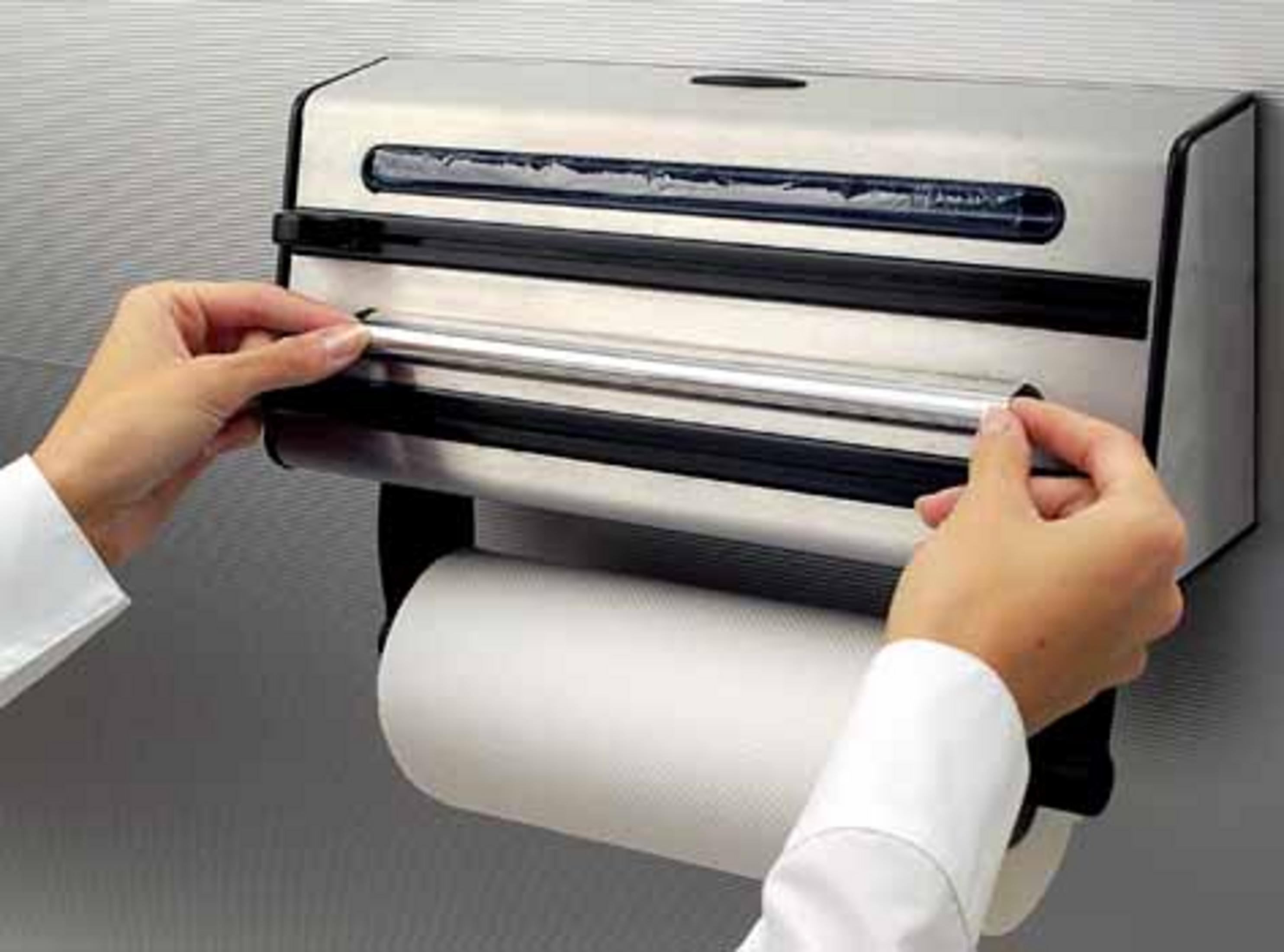 Person benutzt einen silbernen Papiertuchspender mit einer großen Papierrolle.